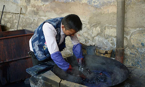 Artisan Duan Shukun works on a tie-dyeing product in Dali, southwest China's Yunnan Province, Nov. 15, 2016. As a traditional folk technique of the Bai ethnic group, tie dyeing was listed in 2006 into state-level intangible cultural heritages. The technique goes through three major steps: making knots, dipping and dyeing, and drying in the sun. The pattern of the cloth is simple and natural, which looks graceful, but not extravagant. Traditional tie-dyeing products are mostly inspired by local scenery and based on blue and white colors. (Xinhua/Li Yan) 