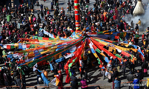 Devotees hang prayer flags to a pole near the Jokhang Temple in Lhasa, capital of southwest China's Tibet Autonomous Region, Feb. 8, 2017. As the Tibetan New Year draws near, prayer flags tied on the five poles surrounding the Jokhang Temple have been replaced by new ones in accordance with Tibetan tradition. (Xinhua/Chogo)