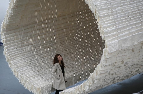 (130228) -- LONDON, Feb. 28, 2013 (Xinhua) -- A working staff watches the monumental rice paper boat by renowned Chinese artist Zhu Jinshi during the media preview of the Art 13 London new modern and contemporary art fair at Olympia Grand Hall in London, Feb. 28, 2013. The 12-metre-long installation made of 8,000 sheets of rice paper and presented by Pearl lam Galleries was built by 20 people over three days and brought to London from Shanghai. (Xinhua/Yin Gang) 