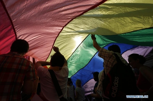 Participants carrying a rainbow flag, symbol of the LGBTQ movement, walk across the city during the Gay Pride Parade in Budapest, Hungary on July 6, 2013. (Xinhua/Attila Volgyi) 