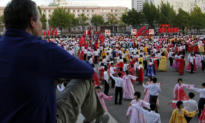 A foreigner watches North Koreans dance in Pyongyang on October 10, 2012. Photo: IC