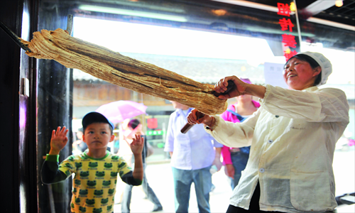 A lady makes candied ginger, which is believed to lessen inner heat. 
