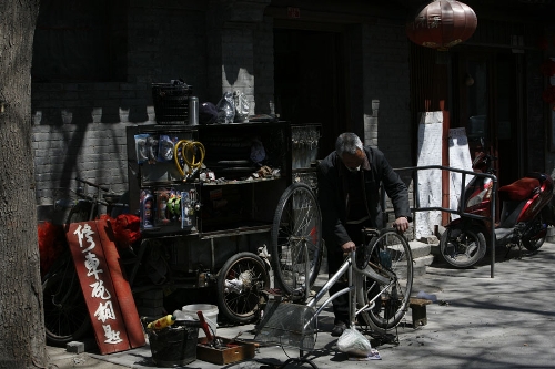 A bicycle repairman in a Hutong(Photo: CRIENGLISH.com/ Wang Zhi)A Hutong is a traditional alley, characteristic of an old Beijing city. A total of 7000 Hutongs have been built throughout the capital in straight lines under strict construction guildlines. The longest Hutong starts from the Beijing Legation Quarter, Dong Jiao Min Xiang,to the Xijiao Min Xiang, and has a total length of 6.5 kilometers, while the shortest Hutong is One-inch Street at only several meters' long. The narrowest Hutong is only about 0.7 meters wide. Therefore, people carrying even a little bit of extra weight have to hold their breath to pass through it. Formed during the Yuan, Ming and Qing, dynasties thousands of Hutongs surround the supreme Imperial Palace from all directions. They are woven into the fabric of people's daily lives.