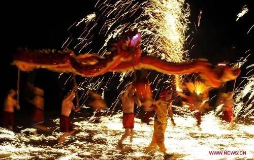 Actors perform dragon dance in firecrackers at the Daguan Park in Kunming, capital of southwest China's Yunnan Province, Feb. 6, 2013. The dance, as a derivative of traditional dragon dance in which performers hold dragon on poles and walk through floods of firecrackers, is a state intangible cultural heritage. (Xinhua/Lin Yiguang) 