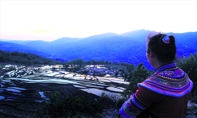 A woman from the Yi ethnic group looks out to the terraced fields in Yunan Province. Photo: CFP