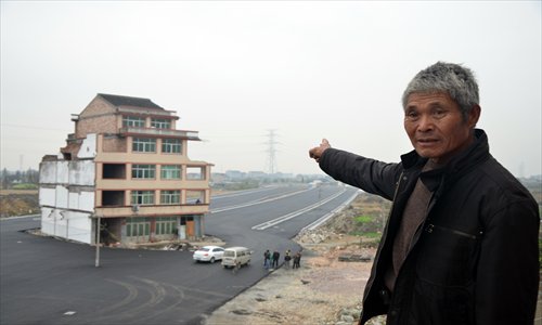 Luo Baogen, 67, points to his house standing in the middle of a new artery leading to the Wenling railway station in Zhejiang Province Wednesday. The man finally agreed to a relocation contract offered by the local government Thursday. Photo: CFP