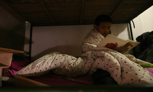 A primary school student wraps up in a quilt at school in Haidian district as the heating system was not available in November, 2011. Many Beijing residents have complained the central heating is not yet working in their homes. Photo: CFP