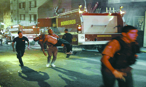 A man carries an injured man, victim of a fire at the Kiss club in Santa Maria, Rio Grande do Sul state, Brazil, early Sunday. At least 245 people were killed during the fire as of press time. Officials say the fire broke out while a band was performing. (See story on page 2) Photo: AP