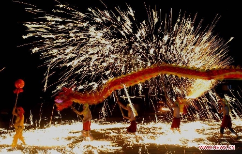 Actors perform dragon dance in firecrackers at the Daguan Park in Kunming, capital of southwest China's Yunnan Province, Feb. 6, 2013. The dance, as a derivative of traditional dragon dance in which performers hold dragon on poles and walk through floods of firecrackers, is a state intangible cultural heritage. (Xinhua/Lin Yiguang) 