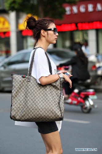 A young woman wearing summer suit walks on road in Nantong City, east China's Jiangsu Province, May 21, 2013. The highest temperature reached 31.9 degrees Celsius on Tuesday. (Xinhua/Xu Peiqin)