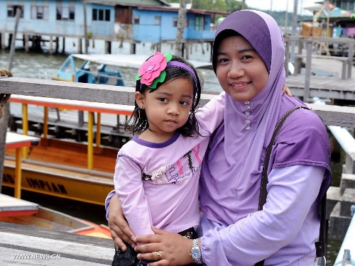 A mother and her daughter pose for photos in the Water Village in Brunei's capital city Bandar Seri Begawan, April 24, 2013. Dubbed as Venice of the East and situated along the Brunei River, Kampong Ayer is the world's largest water village, sheltering about 30,000 inhabitants. It covers an area of 2.6 square kilo-meters and consists of 10 villages whose building are constructed on the Brunei River. (Xinhua/He Jingjia) 