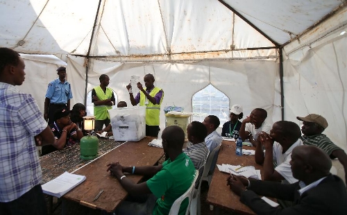 A staff worker (7th L) of Kenya's Independent Electoral and Boundaries Commission (IEBC) shows a ballot paper at a counting station in Nairobi, Kenya, March 4, 2013. Millions of Kenyans turned up early Monday to vote in the historic general elections after independence and in the first national exercise under new constitution after the a disputed polls in 2007. According to the constitution, IEBC will have seven days to officially announce the results, but the country's next president is expected to be known by Monday evening or Tuesday. (Xinhua/Meng Chenguang) 