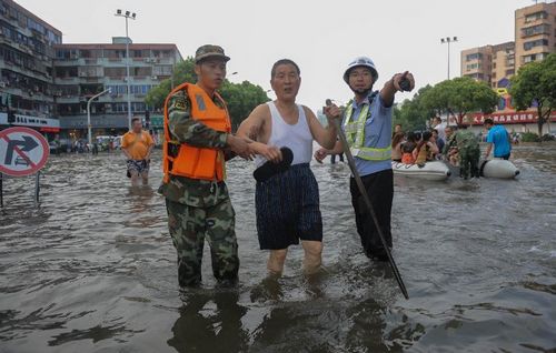 A firefighter and a policeman helps a senior citizen walk through a flooded road in Ningbo, East China's Zhejiang Province, August 9, 2012. As typhoon Haikui landed in Hepu Town of Zhejiang's Xiangshan County early Wednesday, many roads and residential areas were waterlogged after torrential rains in Ningbo. Photo: Xinhua