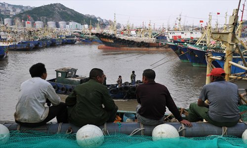 Fishermen, whose boats have been forced to stay in harbor by super typhoon Sanba, sit and chat at a dock in Wenling, Zhejiang Province Sunday, the day they were expecting to set sail following the end of a three-month moratorium on fishing in the East China Sea. Photo: CFP