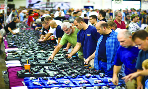 Shoppers examine handguns on display for sale at The Nation's Gun Show held in the Dulles Expo Center in Chantilly, Virginia, US on Saturday. Gun sales have risen in the US in the wake of the movie theatre shooting massacre in Aurora, Colorado on July 20. Photo : CFP 