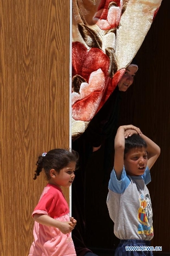 Syrian refugee children stand inside their family caravan at the Mrajeeb Al Fhood refugee camp, 20 km (12.4 miles) east of the city of Zarqa April 29, 2013. The Mrajeeb Al Fhood camp, with funding from the United Arab Emirates, has received about 2500 Syrian refugees so far, according to the Red Crescent Society of the United Arab Emirates. (Xinhua/Mohammad Abu Ghosh) 