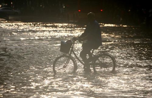 A citizen rides a bike on a flooded road in Ningbo, East China's Zhejiang Province, August 9, 2012. As typhoon Haikui landed in Hepu Town of Zhejiang's Xiangshan County early Wednesday, many roads and residential areas were waterlogged after torrential rains in Ningbo. Photo: Xinhua