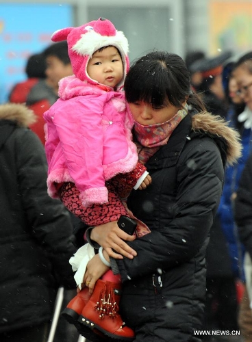 A woman carries her child at the Beijing West Railway Station in Beijing, capital of China, Feb. 3, 2013. Many children travel with their families during the 40-day Spring Festival travel rush which started on Jan. 26. (Xinhua/Chen Shugen) 