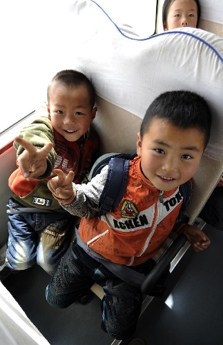 Pupils pose on a school bus in Zhongwei City, northwest China's Ningxia Hui Autonomous Region, March 29, 2013. (Xinhua/Li Ran)