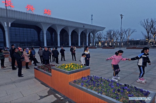 Local residents relax themselve at the aquare along the Changxing Railway Station in Huzhou, east China's Zhejiang Province, Feb. 27, 2013. The 150-kilometer Hangzhou-Ningbo high-speed railway linking Hangzhou and Ningbo, two hub cities in Zhejiang, commenced its integration test here on Friday. Once put into operation on July 2013 as expected, the high-speed railway that designed at a top speed of 350km/h, would reduce the travel time to 36 minitues, a quarter time of the current two-hour journey. (Xinhua/Tan Jin)  