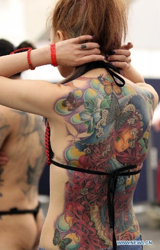 A woman from Asia shows her tattoo during the 21st International Tattoo Convention in Frankfurt, Germany, March 22, 2013. The Tattoo Convention kicked off on Friday and will last for three days. (Xinhua/Luo Huanhuan)