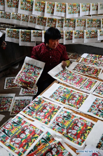 Craftsman Zhai Ruichen's wife Liu Shufang sorts New Year pictures they paints in Liaocheng, east China's Shandong Province, Jan. 9, 2013. The couple were busy painting New Year pictures recently to meet the demand in local market for the Spring Festival in February. (Xinhua/Zhang Zhenxiang) 