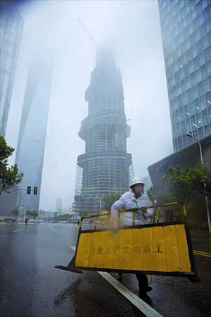 A worker cordons off roads around the construction site of the Shanghai Tower Wednesday. Residents had seen the construction crane at the top of the tower wobbling in the wind. Photo: Cai Xianmin/GT