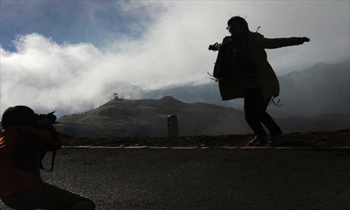 A tourist poses for a photo on the Sichuan-Tibet Highway in Markam County, southwest China's Tibet Autonomous Region, January 1, 2013.