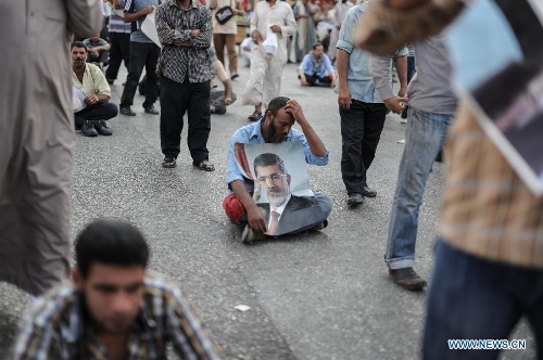 A Morsi's supporter holds up a portrait of Egypt's ousted president Mohamed Morsi as he attends a protest outside the Republican Guards headquarters in Nasr city, Cairo, Egypt, July 6, 2013. (Xinhua/Qin Haishi) 