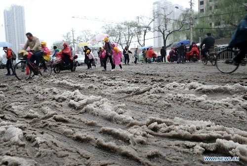 Pedestrians cross a snowy road in Taiyuan, capital of north China's Shanxi Province, April 19, 2013. The city witnessed a snowfall on Friday. (Xinhua/Yan Yan)