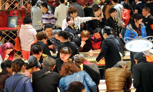 Consumers cram in a gold jewellery shop in Nanjing, capital of east China's Jiangsu Province, April 18, 2013. Gold jewellery shops through China have lowered price of gold jewellery due to the consecutive decline of gold price global markets recently, which boost sales in these shops. Photo: Xinhua