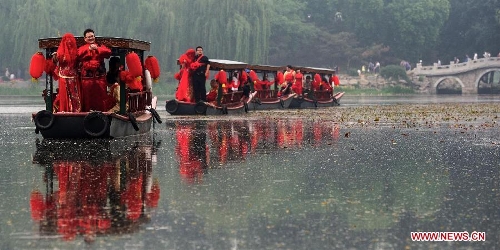 Newlyweds board on boats during a group wedding held in the Old Summer Palace, or Yuanmingyuan park, in Beijing, China, May 18, 2013. A total of 30 couples of newlyweds took part in event with traditional Chinese style here on Saturday. (Xinhua/Luo Xiaoguang)  