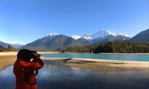 A tourist takes a photo of the scenery in Bome County of Nyingchi Prefecture, southwest China's Tibet Autonomous Region, January 1, 2013.