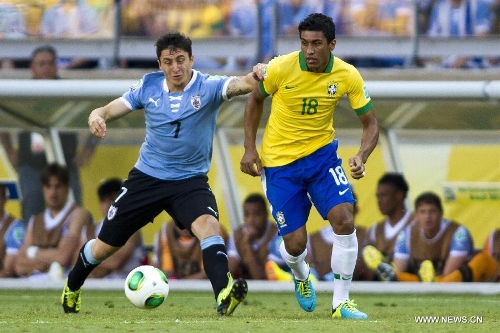 Brazil's Paulinho (R) vies for the ball with Cristian Rodriguez (L) of Uruguay, during the FIFA's Confederations Cup Brazil 2013 semifinal match, held at Mineirao Stadium, in Belo Horizonte, Minas Gerais state, Brazil, on June 26, 2013. (Xinhua/StraffonImages)