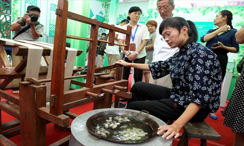 A woman demonstrates the use of a traditional artificial silk reeling machine from Jiangsu Province Tuesday at a Chinese silk festival at Yuyuan Garden. Photo: Xinhua