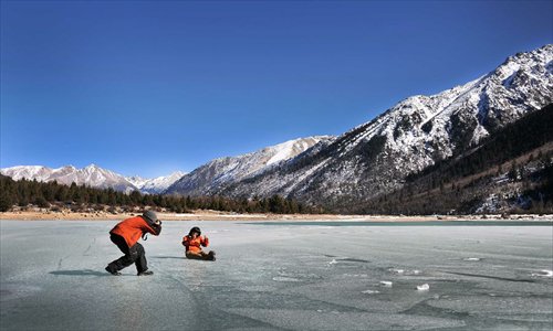 A tourist takes a photo on the frozen Rawok Lake, a famous scenic spot in Baxoi County, southwest China's Tibet Autonomous Region, January 1, 2013.