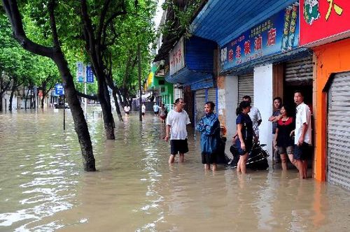 People stand outside a waterlogged store in Fangchenggang city, South China's Guangxi Zhuang Autonomous Region, August 18, 2012. Typhoon Kai-Tak has affected about 1.26 million people and 134,470 hectares of farmlands in Guangxi till 4:30 pm Saturday. Local flood control authority initiated a Level IV emergency response to cope with the possible flooding. Photo: Xinhua