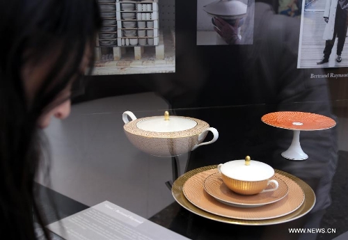 A visitor looks at a set of tableware during an exhibition of 