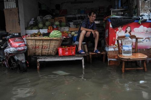 A pedlar sits in his flooded shop in Ningbo, East China's Zhejiang Province, August 9, 2012. As typhoon Haikui landed in Hepu Town of Zhejiang's Xiangshan County early Wednesday, many roads and residential areas were waterlogged after torrential rains in Ningbo. Photo: Xinhua