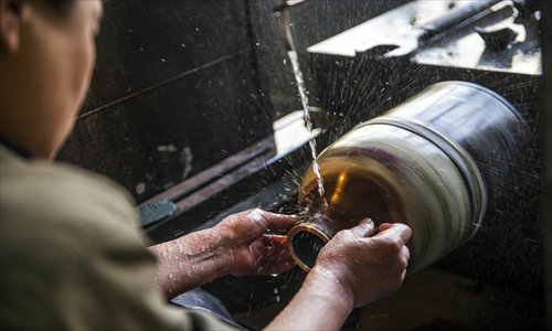 5. The craftsman polishes the piece with a small grindstone he holds in his 
right hand. Photos: Li Hao/GT