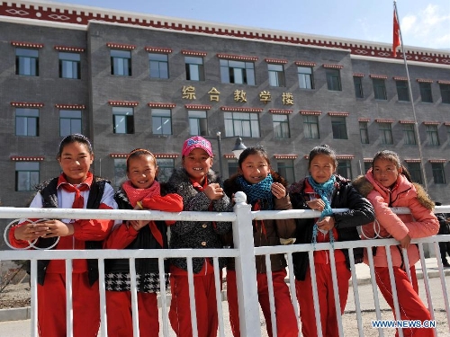 Pupils of the Tibetan ethnic group pose for photos in front of a Tibetan-style teaching building at No. 1 Primary School of Deqin County in Diqing Tibetan Autonomous Prefecture, southwest China's Yunnan Province, March 12, 2013. A total of 1,260 pupils, most of whom are of the Tibetan ethnic group, study at this school, which was founded in September 2012. Pupils here are offered free meals and lodging. (Xinhua/Lin Yiguang) 