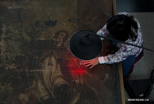 A restorer works on a painting in the restoration and conservation workshop of the Centro Tarea of the San Martin University, in the city of Buenos Aires, Argentina, on May 21, 2013. Within the spectra of tangible heritage objects, the Centro Tarea has specialized in the conservation and restoration of the picture and sculpture production, as well as in the conservation and restoration of bibliographic documentation and archive. (Xinhua/Martin Zabala)