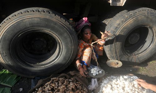 An Indian vendor sells vegetables sitting under a truck outside a market in Kolkata on Wednesday. The Indian Meteorological Department has backtracked on their projections of monsoon revival, declaring that the country will have 