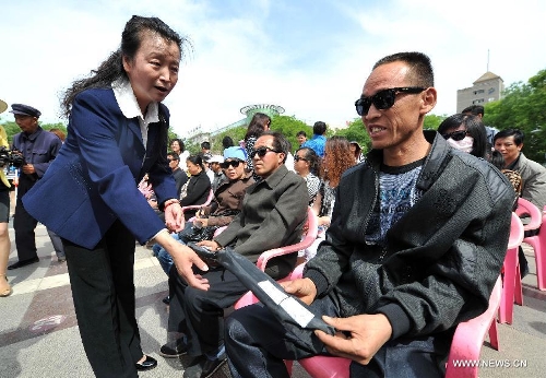 A worker distributes crutches to blind people at the Yuhuangge Square in Yinchuan City, capital of northwest China's Ningxia Hui Autonomous Region, May 14, 2013. An activity aimed at helping the blind to walk was held here on Tuesday, in which more than 100 blind people were provided with crutches as they were helped to walk with them ahead of the 23rd national day for helping the disabled on May 19. (Xinhua/Peng Zhaozhi) 