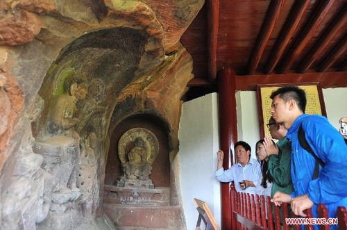 Tourists visit a grotto sculpture in the Shibao Mountain of Jianchuan County in Dali Bai Autonomous Prefecture, Southwest China's Yunnan Province, August 9, 2012. A wide range of subject matters are featured in the grottos, including political life of the Nanzhao Dynasty (738-902), Buddhist figures and religious beliefs of the Kingdom of Dali. The grottos here were listed into the first batch of China's historic and cultural sites in 1961. A total of 16 grottos and 139 sculptures were open to the public so far. Photo: Xinhua