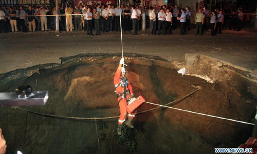 A firefighter rescues citizens at an accident site after a road collapsed at Liaoyang street of Harbin city, Northeast China's Heilongjiang Province, August 14, 2012. Two people were confirmed dead and two others injured when a roadbed collapsed at Liaoyang Street in Nangang district of Harbin city on Tuesday. Photo: Xinhua