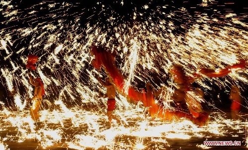 Actors perform dragon dance in firecrackers at the Daguan Park in Kunming, capital of southwest China's Yunnan Province, Feb. 6, 2013. The dance, as a derivative of traditional dragon dance in which performers hold dragon on poles and walk through floods of firecrackers, is a state intangible cultural heritage. (Xinhua/Lin Yiguang) 