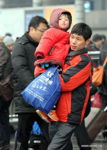 A man carries his child at the Beijing West Railway Station in Beijing, capital of China, Feb. 3, 2013. Many children travel with their families during the 40-day Spring Festival travel rush which started on Jan. 26. (Xinhua/Chen Shugen)  