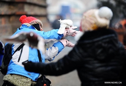 People play with pigeons in Harbin, capital of northeast China's Heilongjiang Province, Jan. 20, 2013. The temperature rise in Harbin enabled citizens to play with snow and ice in the outdoors. (Xinhua/Wang Kai) 