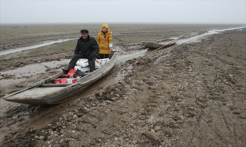 A small skiff loaded with donated relief supplies for Spring Festival is pulled across the mud flats.Photo:CFP